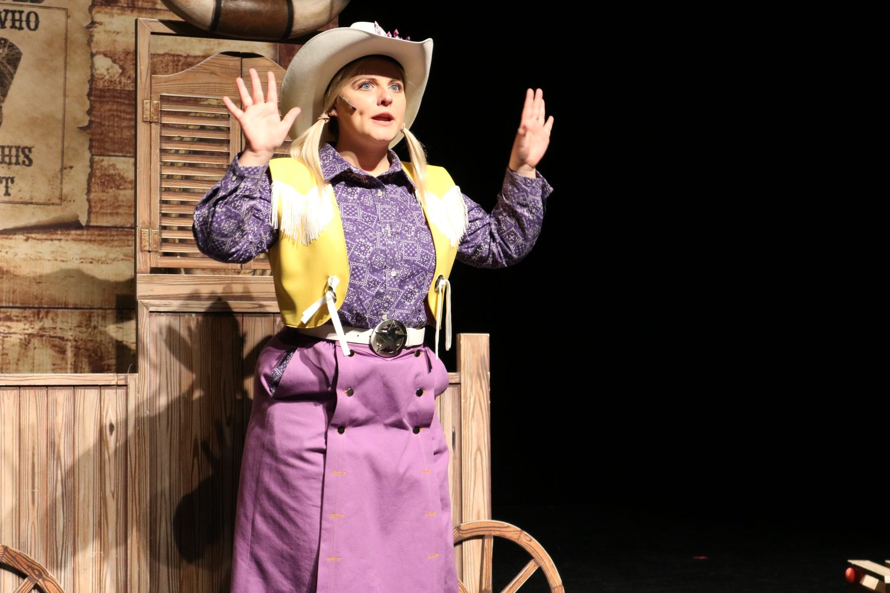 actor in purple shirt and skirt in cowboy hat