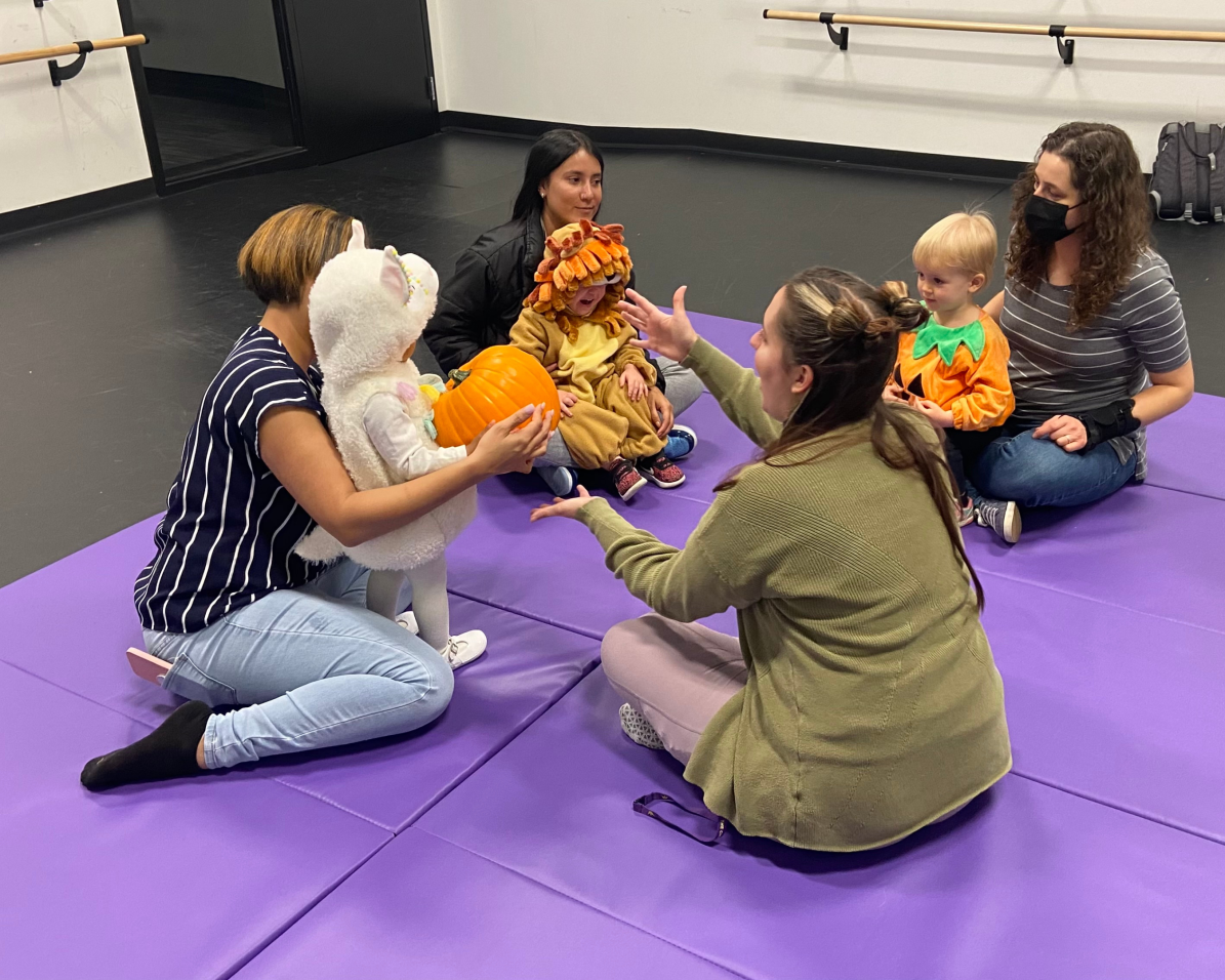 group of moms and babies passing a pumpkin