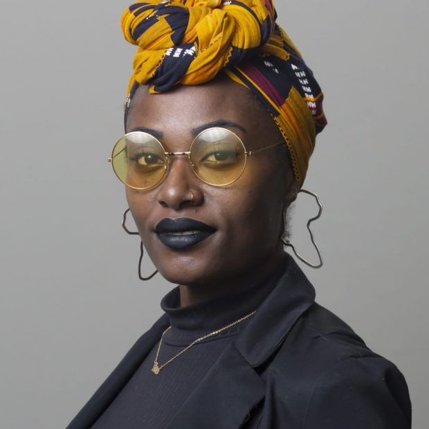 woman in yellow headwrap and glasses wearing black shirt