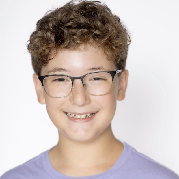 Boy with glasses and purple shirt smiling