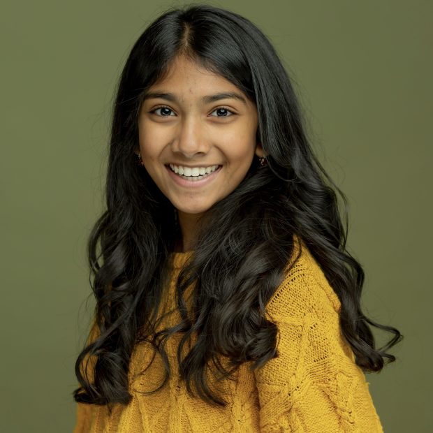 Young girl in yellow sweater with black hair and green background