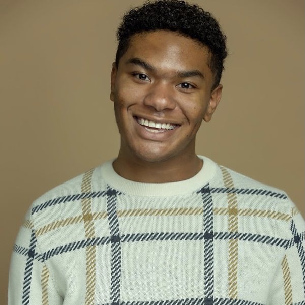 Young man in cream patterned sweater with light brown background