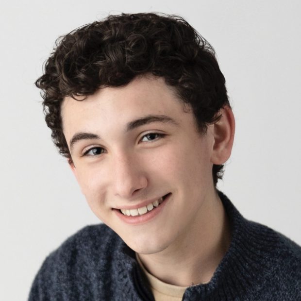 Boy with curly hair and navy sweater smiling