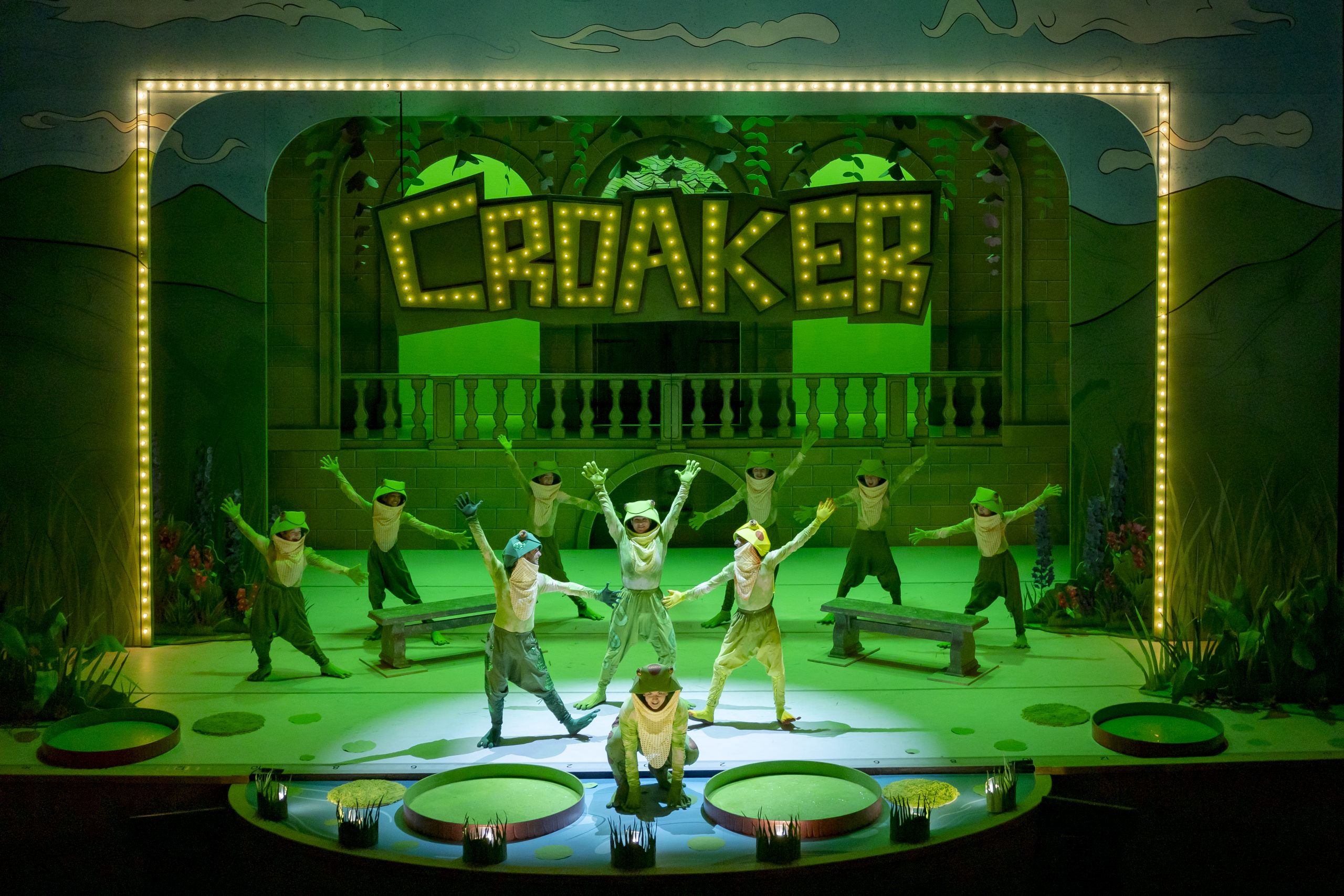 Croaker marquee sign with green set and performers in frog costumes