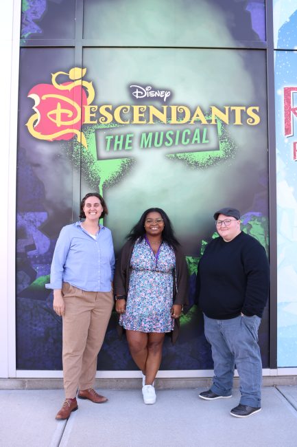 three people standing in front of Descendants poster