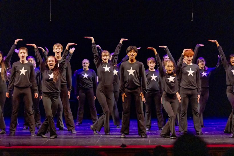 Kids posing and singing on stage in star shirts